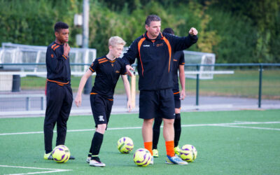 Sportpsycholoog in trainingspak samen met de coach op het veld